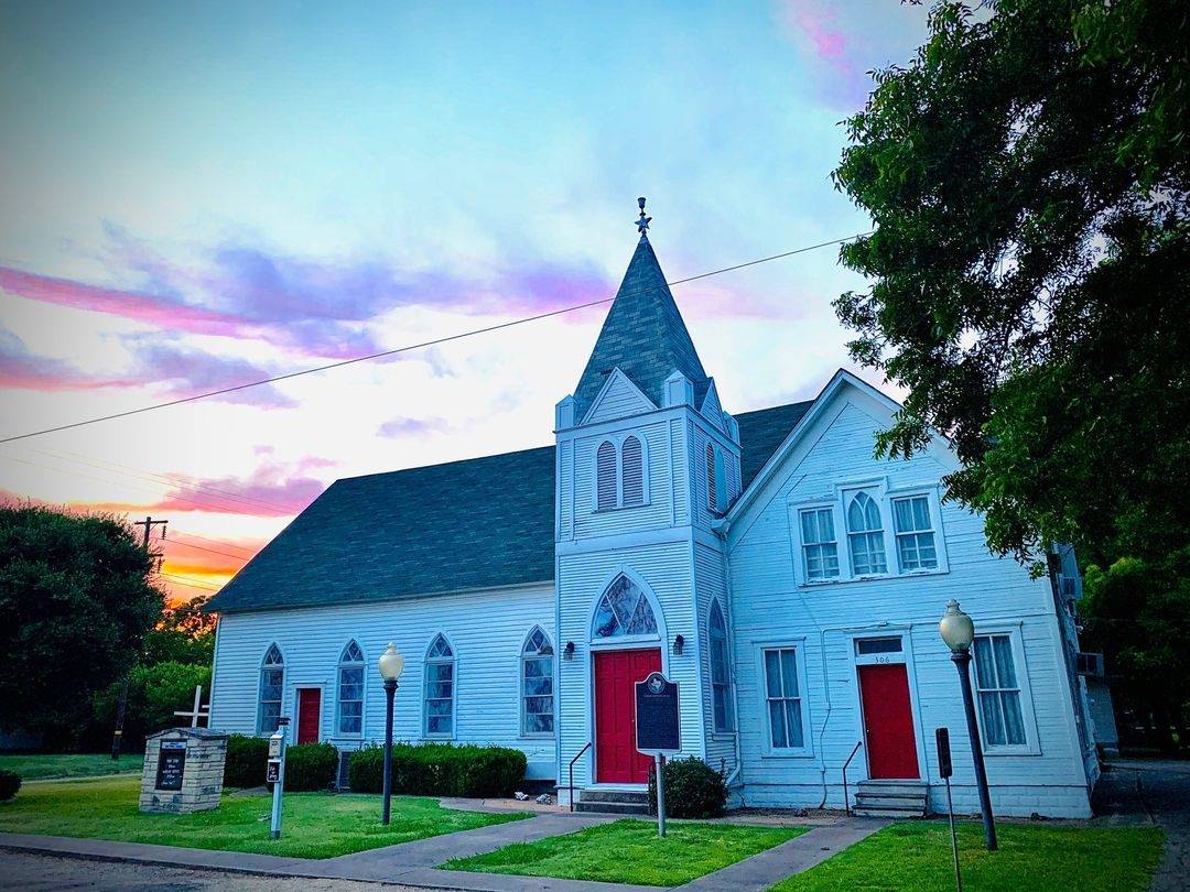 The Granger Brethren Church at sunset, the sky pink and lavender behind the steeple.